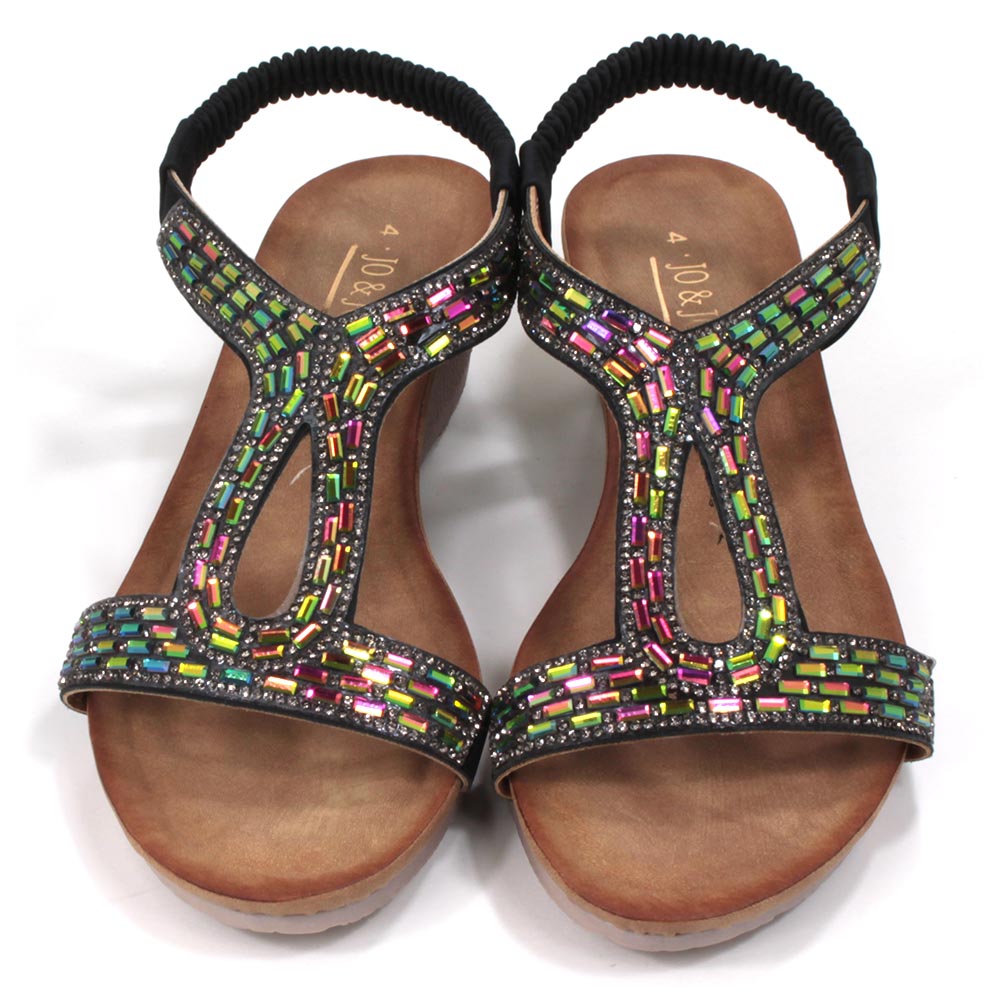 Sandals with black elasticated ankle straps. Over feet straps decorated with mosaics of sparkling jewels. Tan coloured insoles. Low heels. Front view.