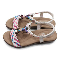 Beige sandals with colorful braided straps on a white background
