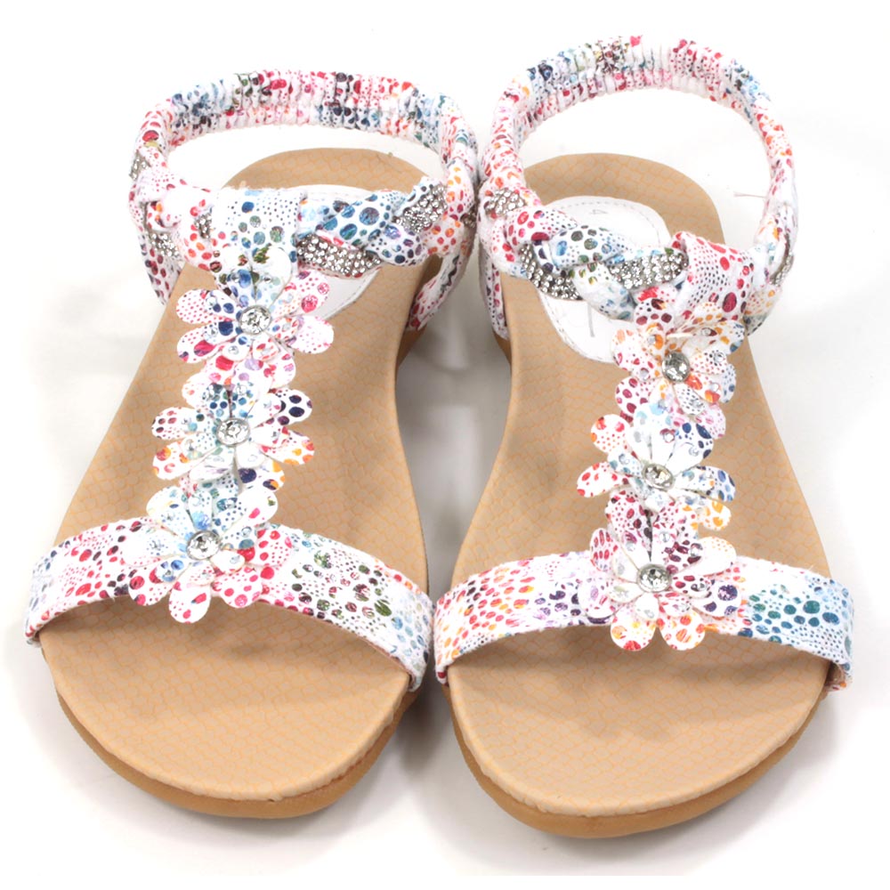 Flat sandals with white straps decorated with multi coloured pattern. Floral detailing over the feet. Elasticated heel straps. Front view.