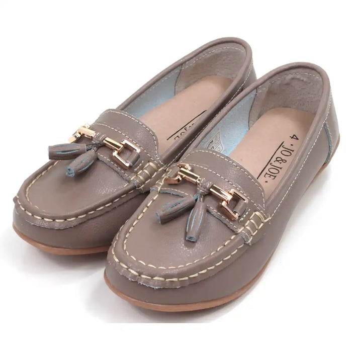 Pair of beige moccasins  with decorative gold bars and tassels on a white background