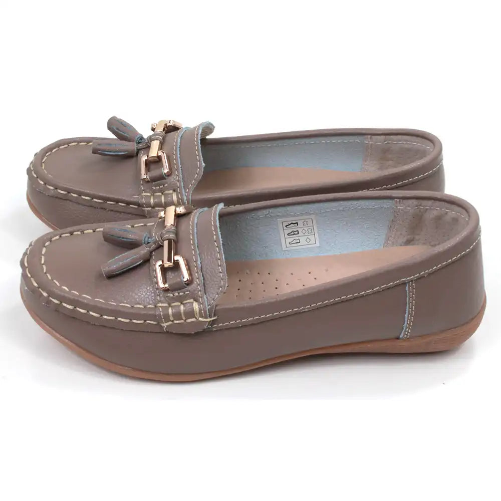 Pair of beige moccasins  with decorative gold bars and tassels on a white background