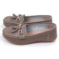 Pair of beige moccasins  with decorative gold bars and tassels on a white background