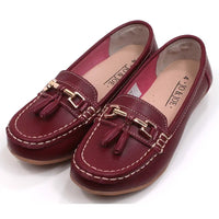 Joe and Jo moccasin style slip on, leather shoes in red wine colour. Over the foot metallic gold coloured  detail and two matching tassels. Beige rubber soles. Angled view.