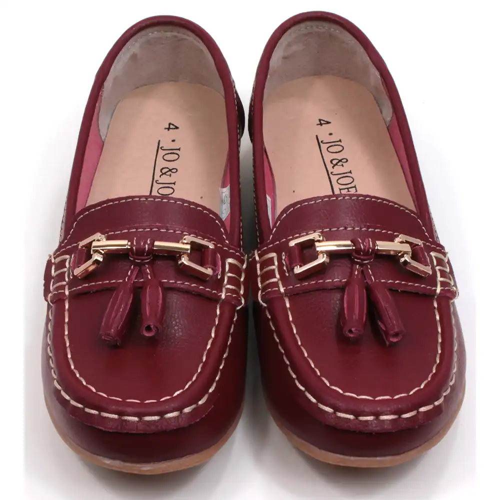 Joe and Jo moccasin style slip on, leather shoes in red wine colour. Over the foot metallic gold coloured  detail and two matching tassels. Beige rubber soles. Front view.