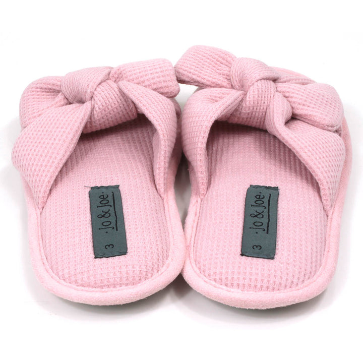 Pink slip on slippers with open toes and open backs. Pink waffle fabric. Padded footbed. Large bow over the foot. Back view.