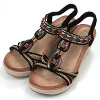 Black, strappy, wedge sandals. Peep toed with beads and fabric decoration on the straps. Elasticated slingback fitting. Hessian look wedge heels and sole sides. Angled view.