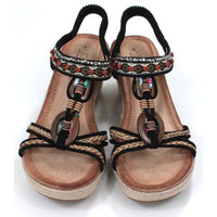 Black, strappy, wedge sandals. Peep toed with beads and fabric decoration on the straps. Elasticated slingback fitting. Hessian look wedge heels and sole sides. Front view.