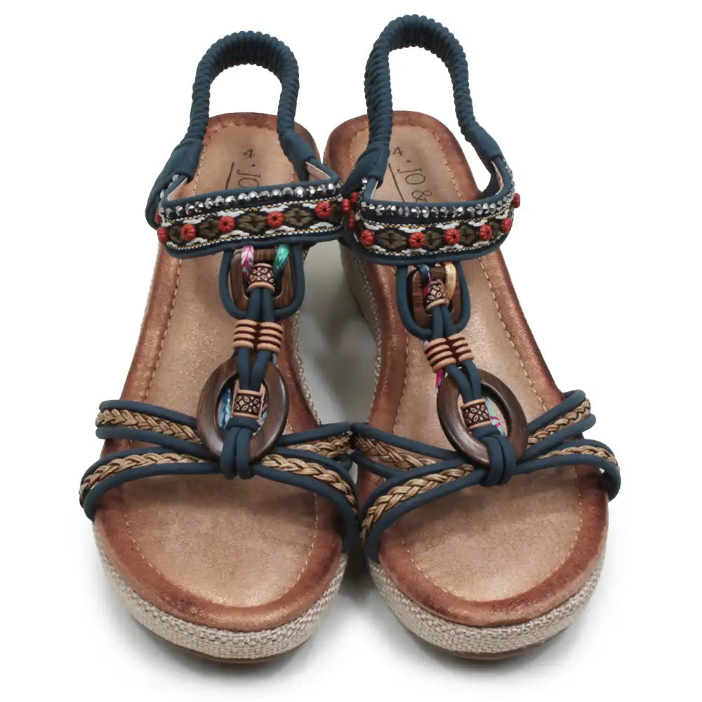A pair of women's wedge sandals with navy blue straps, braided details, colorful beadwork, and brown espadrille-style soles, shown on a white background.
