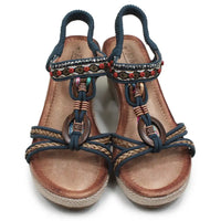 A pair of women's wedge sandals with navy blue straps, braided details, colorful beadwork, and brown espadrille-style soles, shown on a white background.