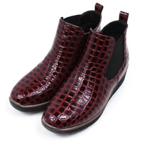 Pair of burgundy crocodile-patterned boots. Angled view.