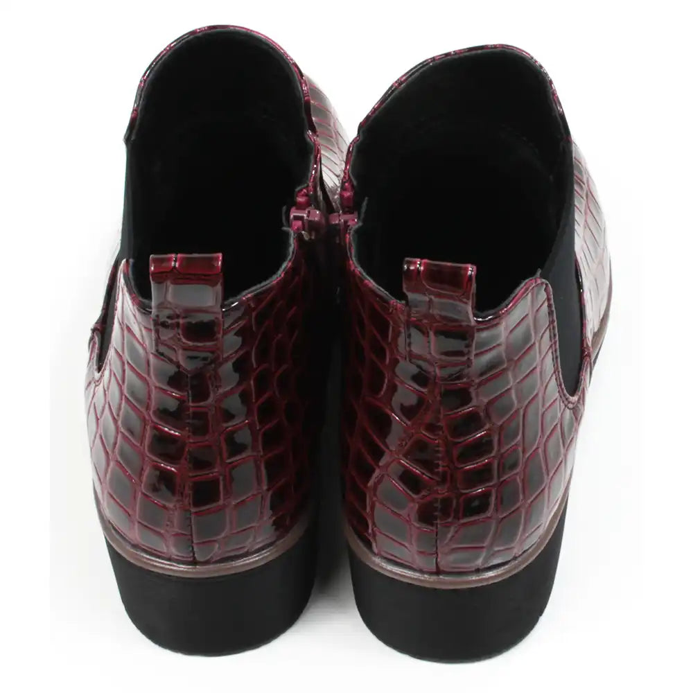 Pair of burgundy crocodile-patterned boots. Back view.