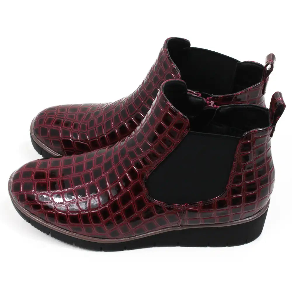 Pair of burgundy crocodile-patterned boots. Side view.