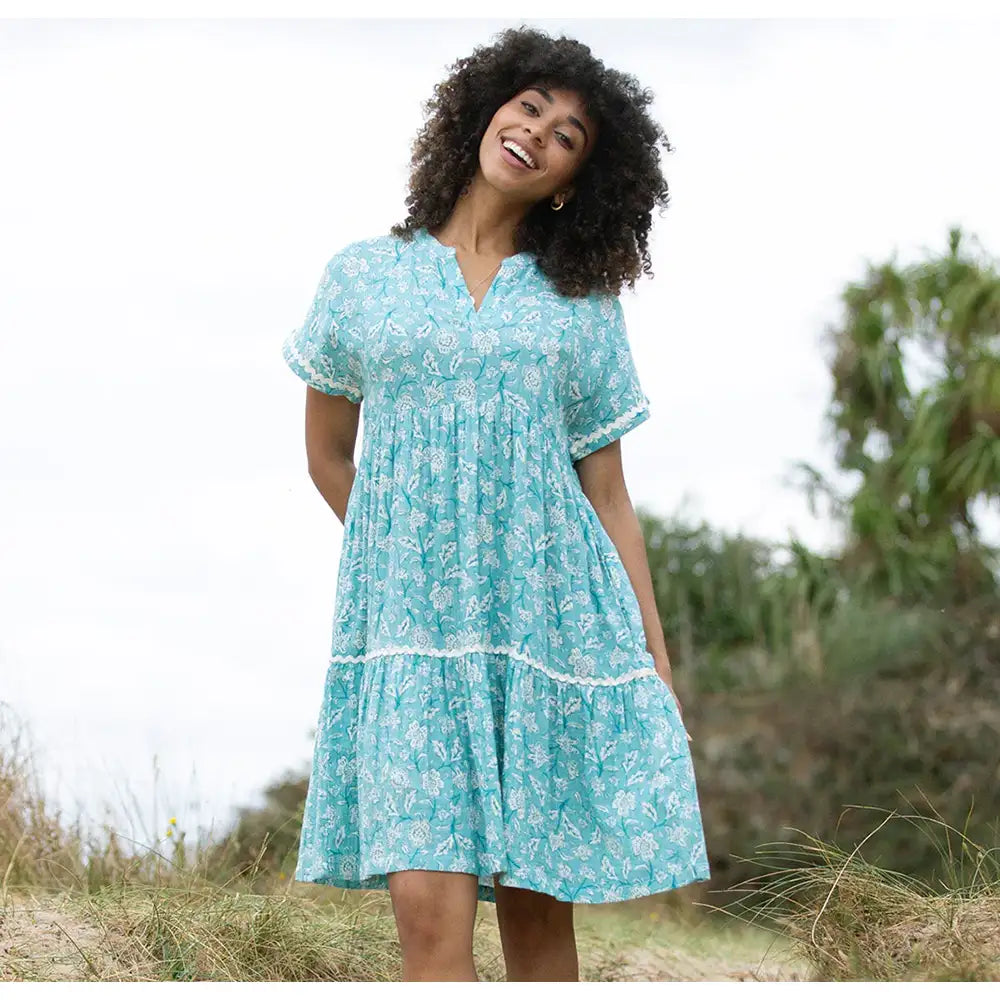 Front of a pale blue dress with a floral paisley print in white. Short sleeves, knee length and v neckline. 