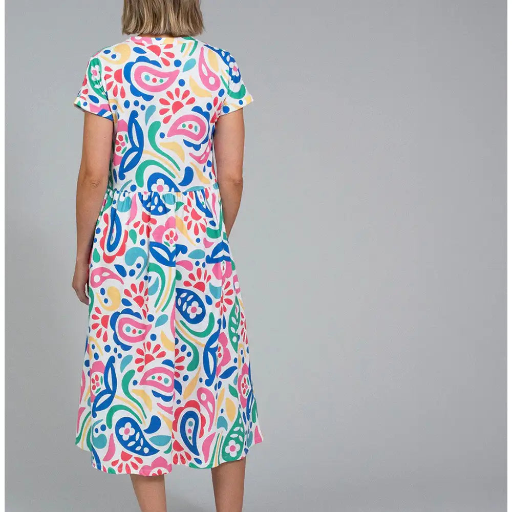 Back  of a white based dress with a large rainbow coloured paisley print. Dress has short sleeves and falls to below the knee.
