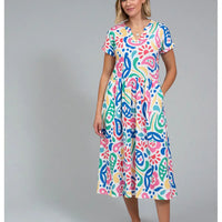 Front of a white based dress with a large rainbow coloured paisley print. Dress has short sleeves and falls to below the knee.