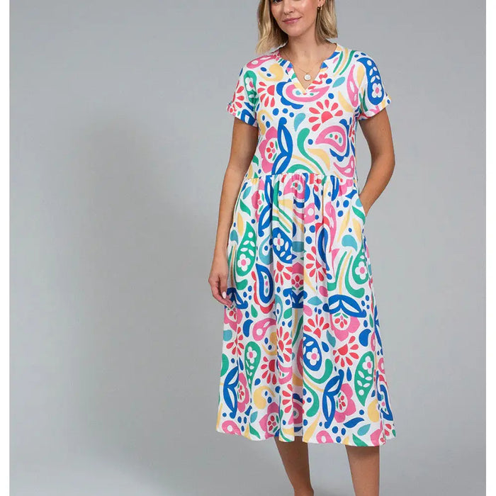 Front of a white based dress with a large rainbow coloured paisley print. Dress has short sleeves and falls to below the knee.