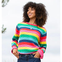 The front of a rainbow striped knitted jumper with a zig zag cut out design. 