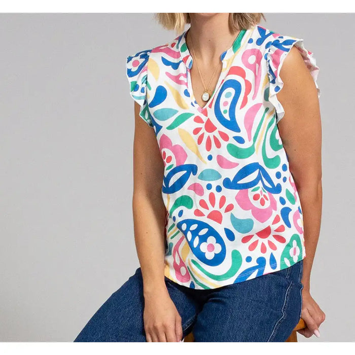 Woman wearing a colorful patterned blouse with a plain background