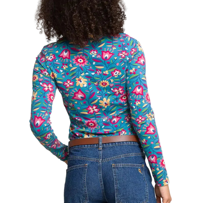 A woman shown from the back wearing a fitted long-sleeve top with a dense floral and botanical print in bright teal, pink, yellow, and green. 