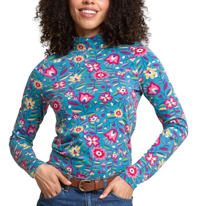 A woman wearing a long-sleeve turtle neck top with a colourful floral and bird pattern on a teal background. 