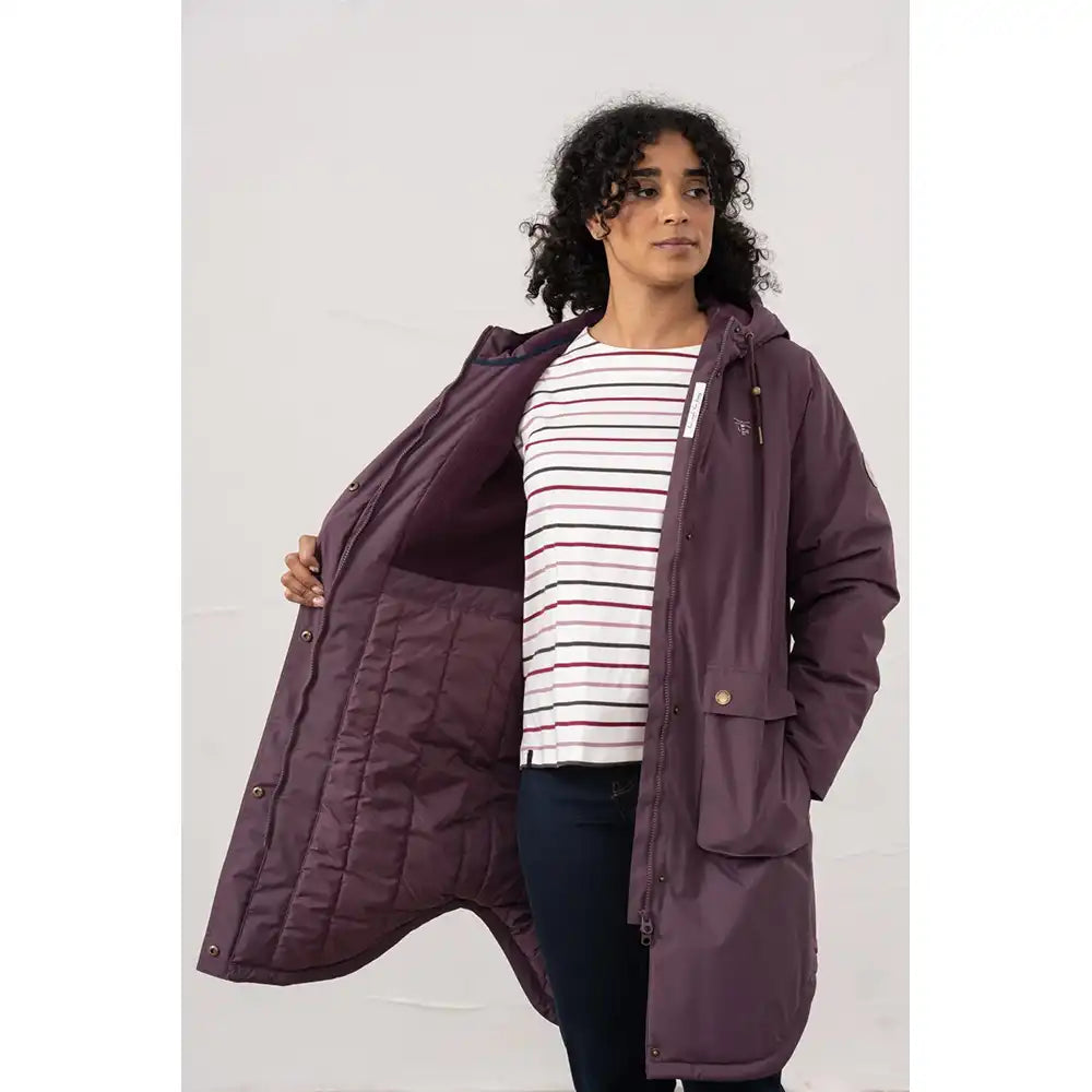 Woman wearing a long purple coat over a striped shirt on a white background