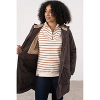 Woman wearing a brown jacket over a striped shirt with a white background