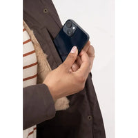 Person holding a smartphone with a coat pocket in the background