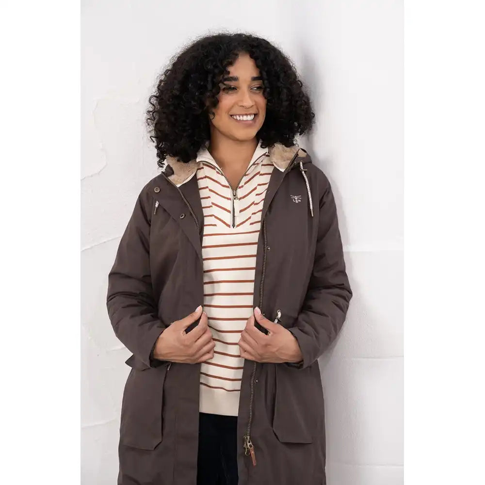 Person wearing a brown coat over a striped shirt against a white background