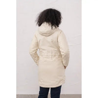 Person wearing a beige puffer coat against a white wall