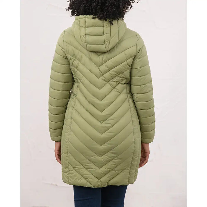 A person shown from the back wearing a hooded quilted puffer coat in an olive green color, paired with dark blue jeans, against a plain off-white wall.