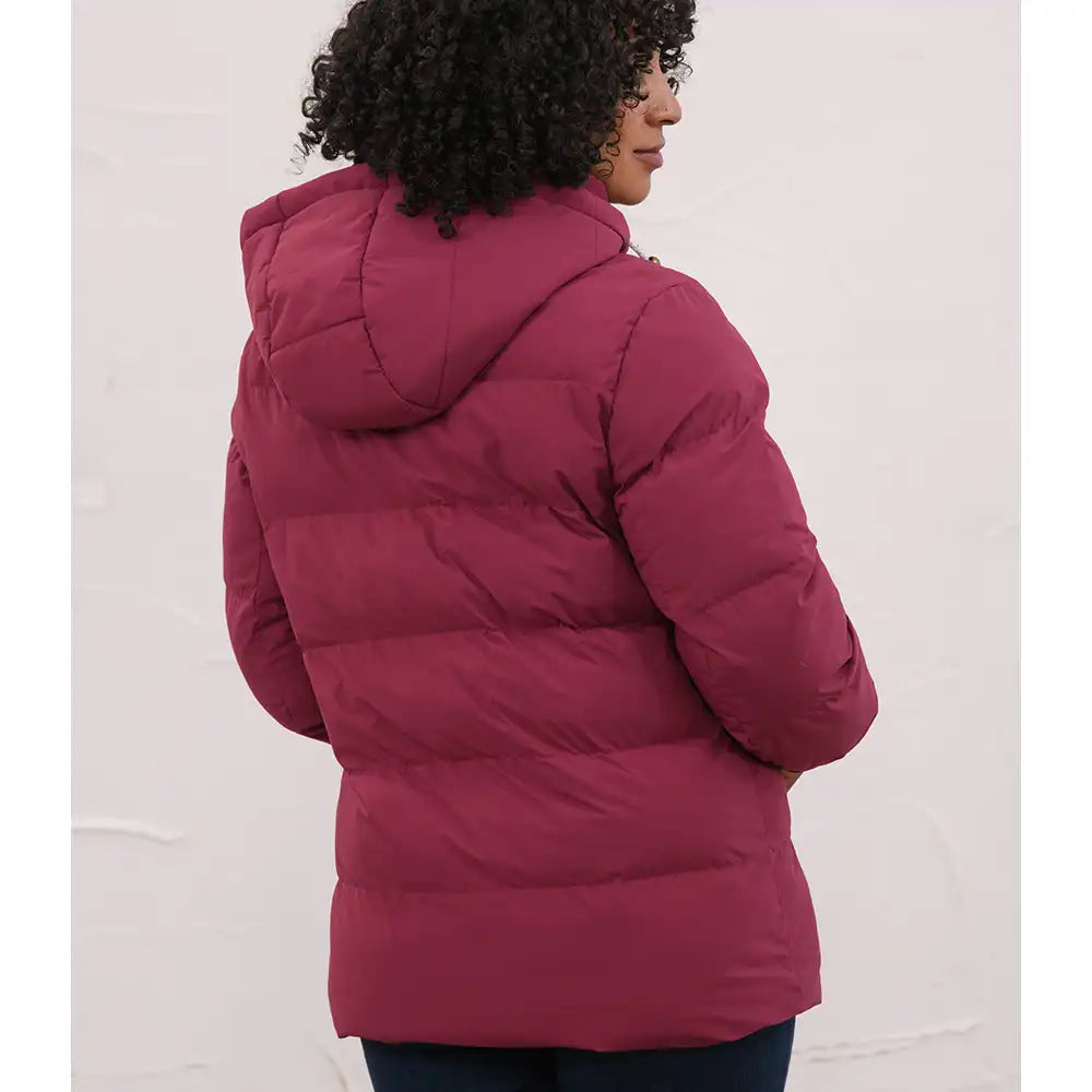 A person shown from the back wearing a quilted puffer jacket in a deep berry pink or burgundy tone, standing against a plain light wall.