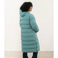 A woman wearing a long, puffer-style hooded coat in a muted teal-green color, shown from the back against a plain off-white wall.