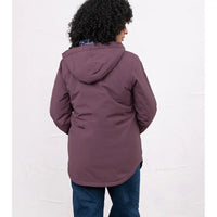 A person shown from the back wearing a muted plum-purple hooded jacket and blue jeans against a plain white studio background.