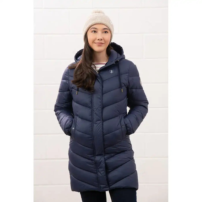 Woman wearing a blue puffer coat and beige beanie against a white background