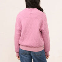 A person shown from the back wearing a pink quilted bomber-style jacket with a diamond-quilted pattern, ribbed collar, cuffs, and hem, paired with blue jeans against a plain off-white background.