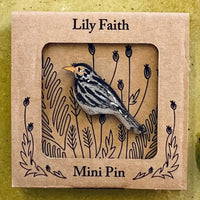A wooden blackbird mini pin with a small yellow beak, displayed inside a square kraft paper window box labeled 'Lily Faith' and 'Mini Pin'.