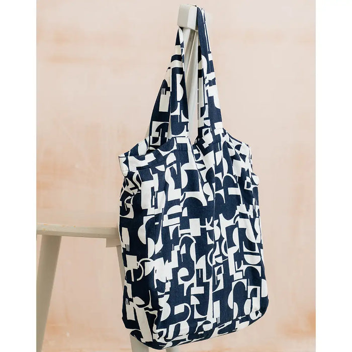 Navy blue and white patterned reusable bag hanging on a wooden surface