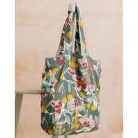 Floral patterned tote bag hanging on a chair against a beige background