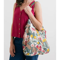 Woman holding a floral-patterned bag against a white background