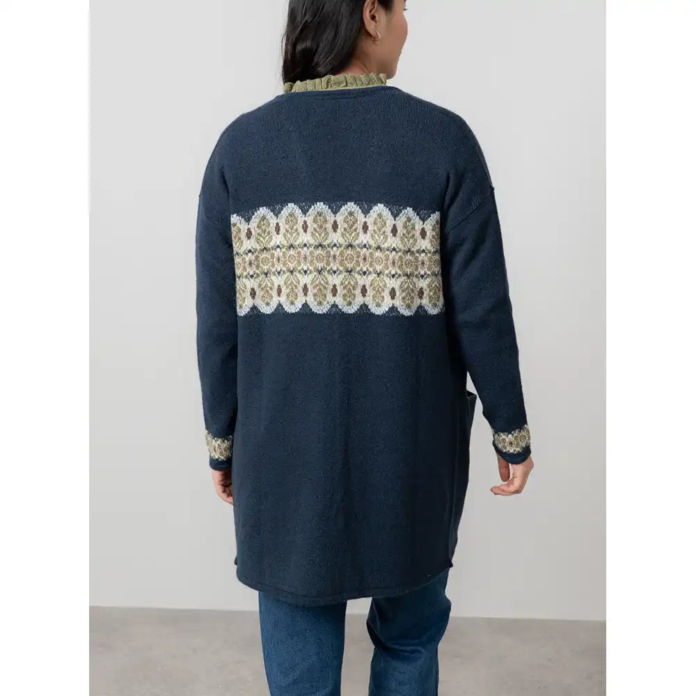 Person wearing a navy blue long-sleeve shirt with patterned trim on a plain background