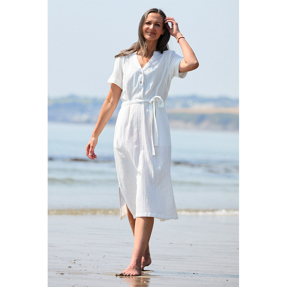 Women wear a mid-calf white dress that has short sleeves, V neckline with button accents and a  tie belt at the waist line 