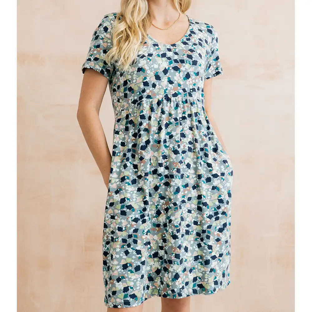 Woman wearing a short-sleeve, floral-patterned dress against a beige background