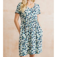Woman wearing a short-sleeve, floral-patterned dress against a beige background