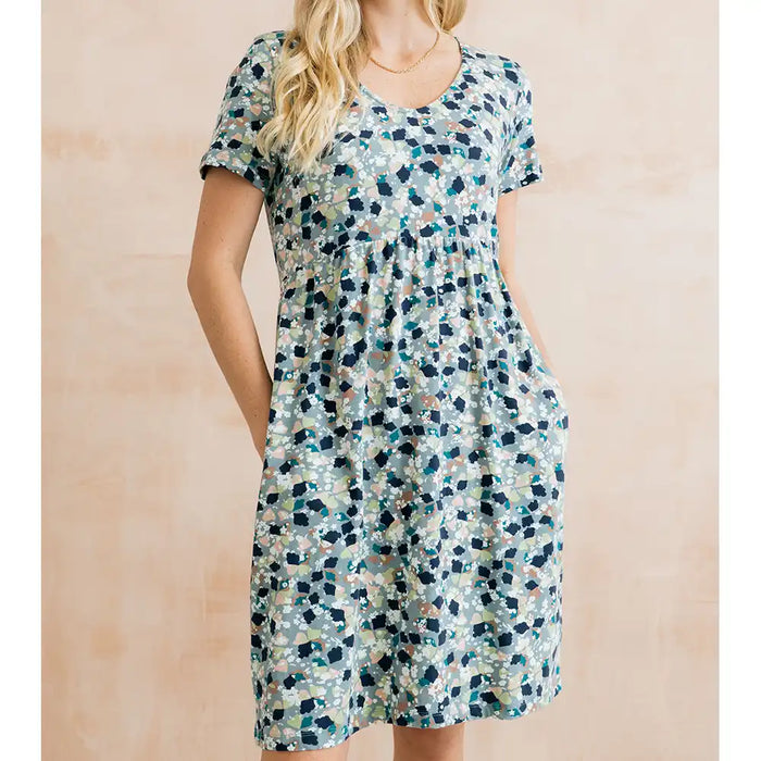 Woman wearing a short-sleeve, floral-patterned dress against a beige background