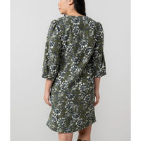 Woman wearing a green floral dress against a plain background