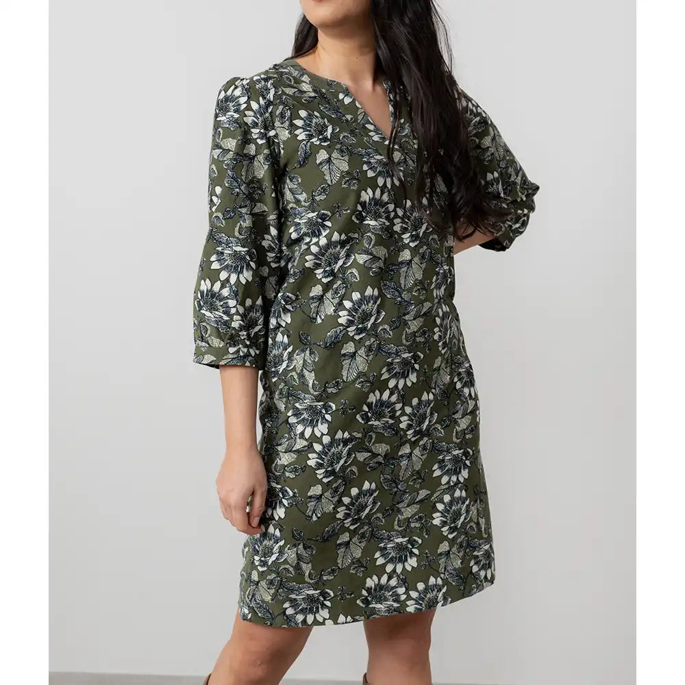Woman wearing a green floral dress against a white background