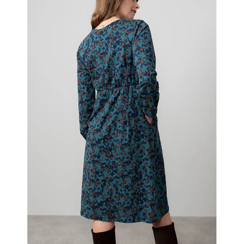 Woman wearing a long blue floral dress against a plain background