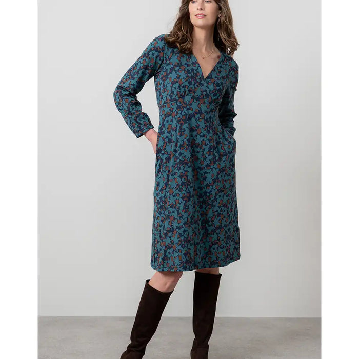 Woman wearing a blue floral dress with brown boots on a white background