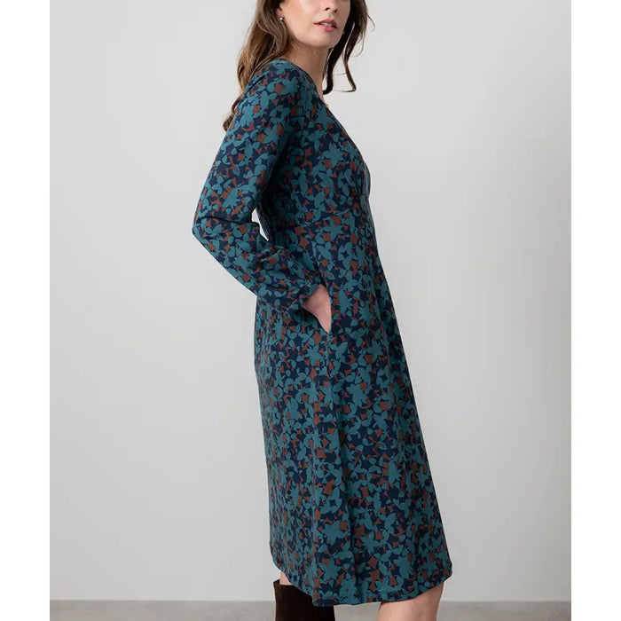 Woman wearing a long floral dress against a plain background