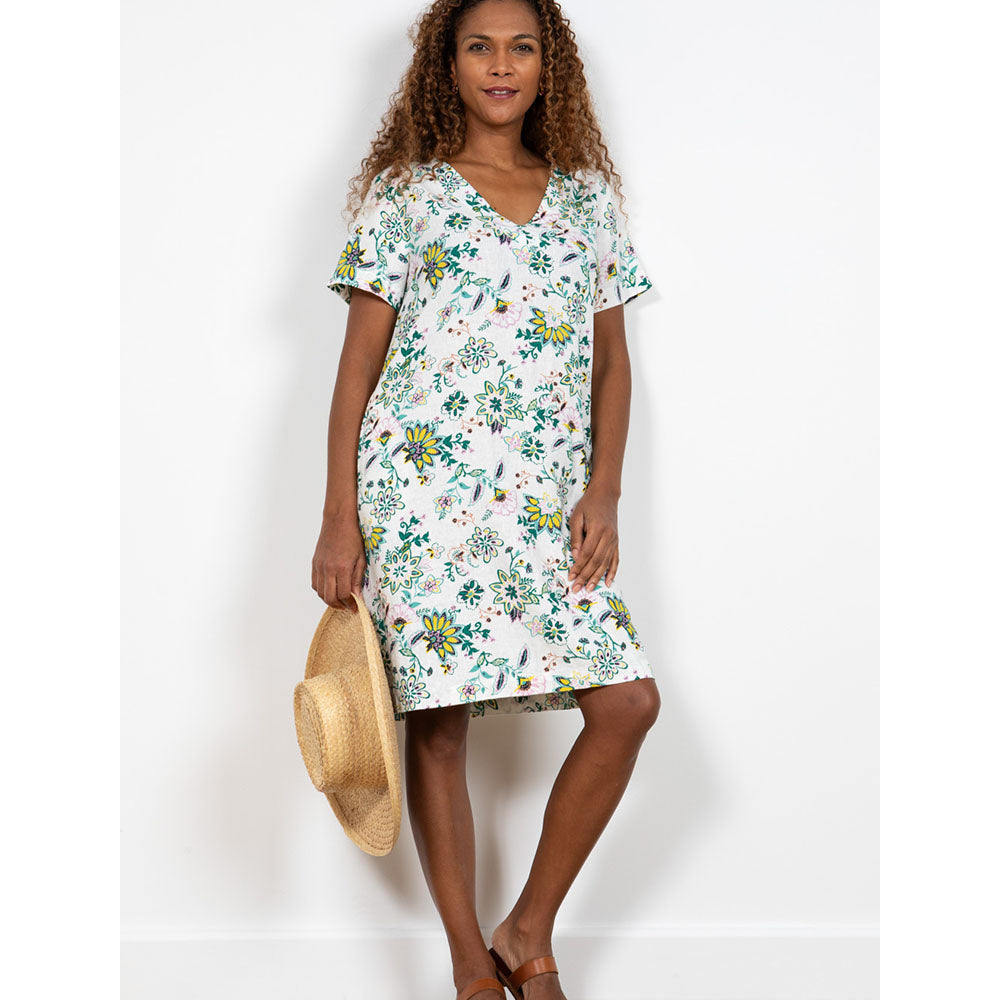 Front of white V neck dress with short sleeves that comes to the knee with the tree of life and flowers on in greens, yellow and pale pink 